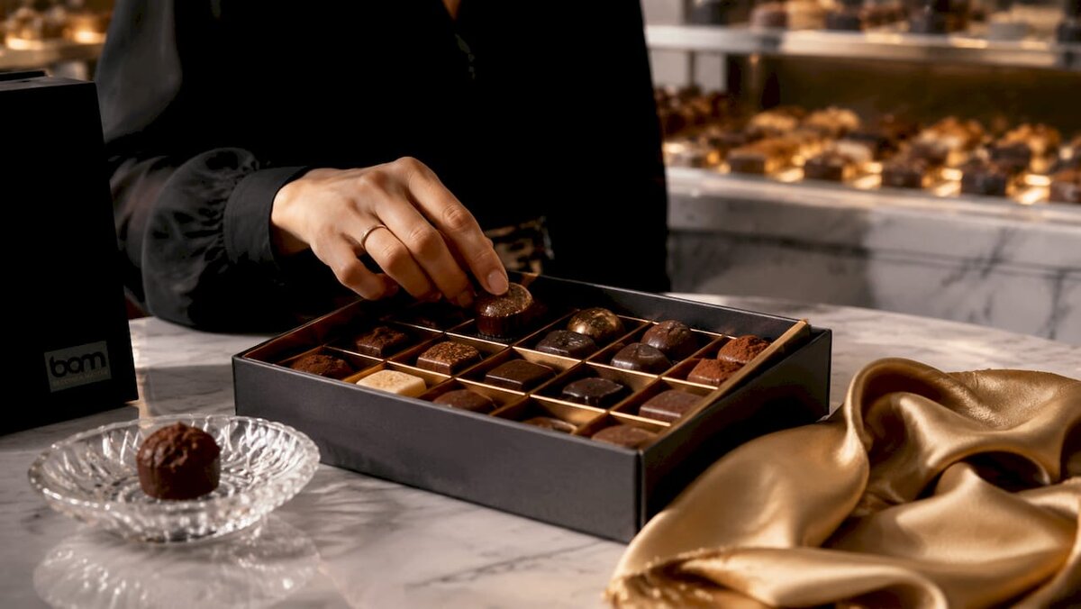 Assortiment de chocolats dans une boîte cadeau ouverte, accompagné d'un guide des saveurs