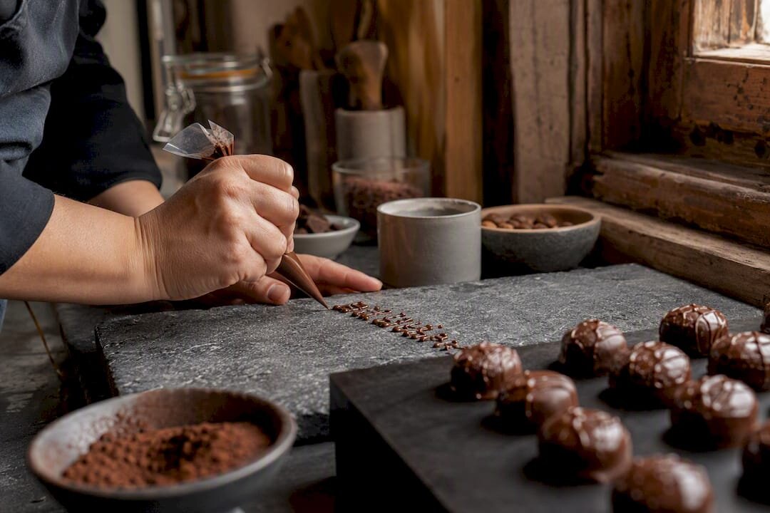 Des mains en train de décorer des lettres en chocolat personnalisées